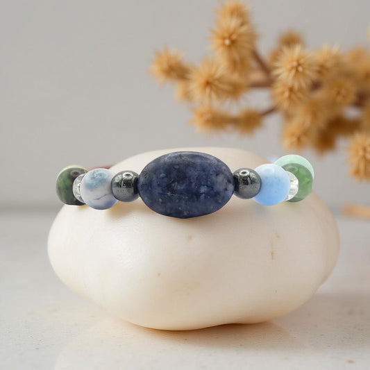 Mercury retrograde elastic bracelet with an oval blue sodalite bead at the center with other crystals such as blue lace agate, clear quartz, green and purple fluorite and other gemstones in a symmetrical pattern. In soothing cool tones  along with hematite and pyrite which have a metallic finish.