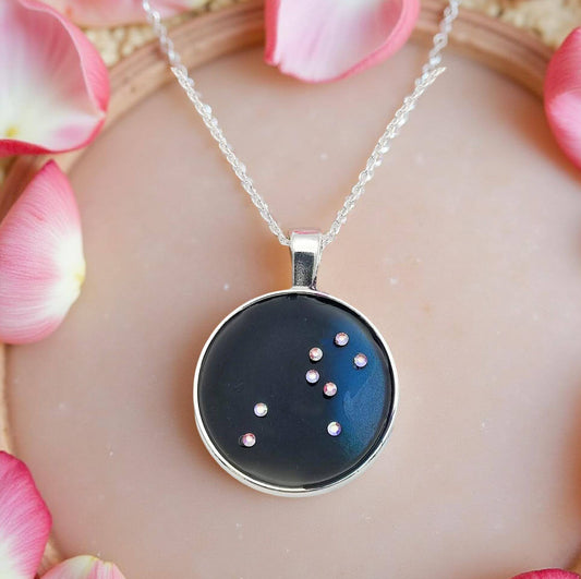 Dark blue with iridescent sparkling swirls of pinks, purples, silver, and monochromatic shades of blue enamel. With handset Aurora Borealis rhinestones to represent the star of the constellation of Leo. The pendant is 1 inch silver toned with a 1/4th inch bail on a silver toned chain.