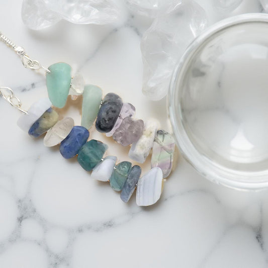 Assorted chipped crystals including sodalite, blue lace agate, amazonite, clear quartz and green fluorite. Hanging on a silver toned fishhook, with the gemstones a-lined on a 2 1/4th inch drop in a random but  complementary order. 