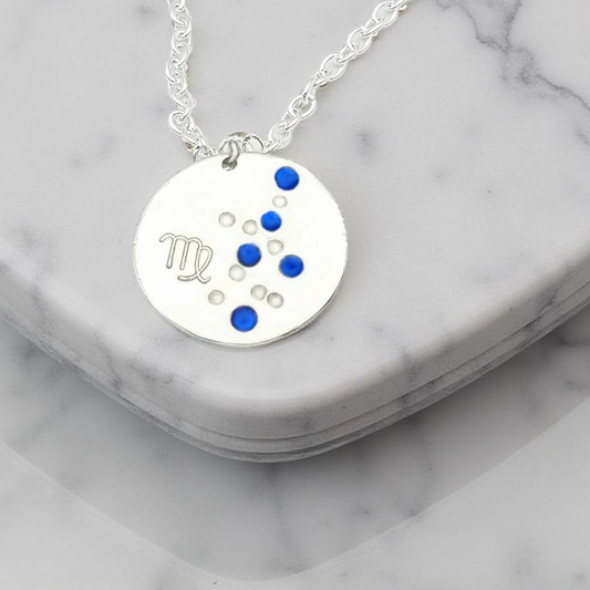 September Virgo necklace pendant with hand set sapphire colored glass rhinestones forming the constellation of Virgo. Hand stamped with the zodiac symbol for Virgo, on a 3/4th of an inch silver toned circle hanging from a silver toned chain.